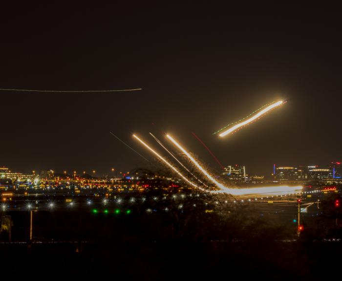 Airplanes taking of at night with streams of light visible