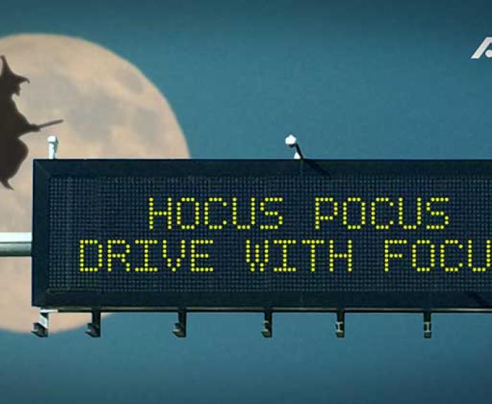 Highway sign reads HOCUS POCUS DRIVE WITH FOCUS with a silhouette of a witch on a broomstick flying in front of a full moon in the background. ADOT logo appears in the upper right corner.