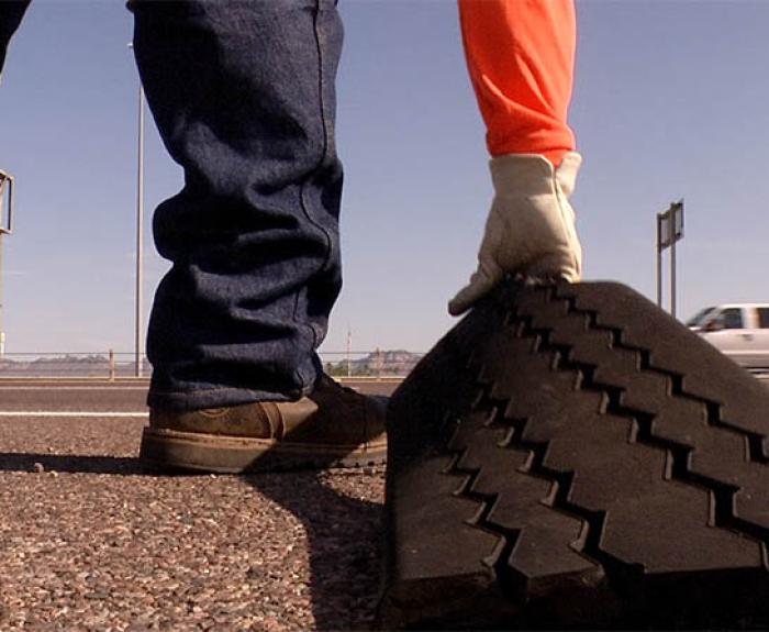 Worker removes tire tread from side of freeway