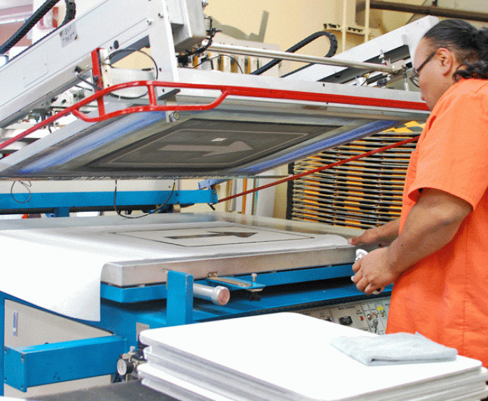 Worker uses printing machine in ADOT sign shop