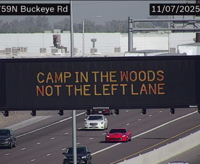 A digital message board on the highway encouraging drivers to not camp in the left lane.