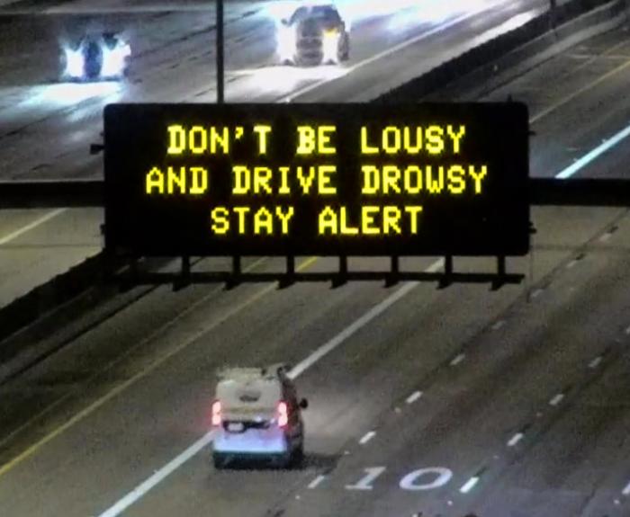 A digital message board on the highway encourages motorists to stay alert.