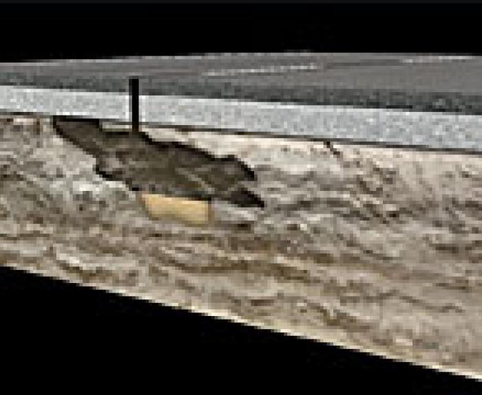 Cross-section of a road showing a cavity or void beneath the surface pavement layer.
