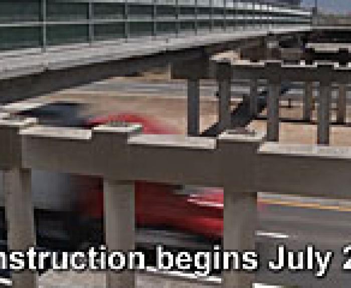 Partially constructed overpass above a highway with a red truck passing underneath; text reads Construction begins July 2011.
