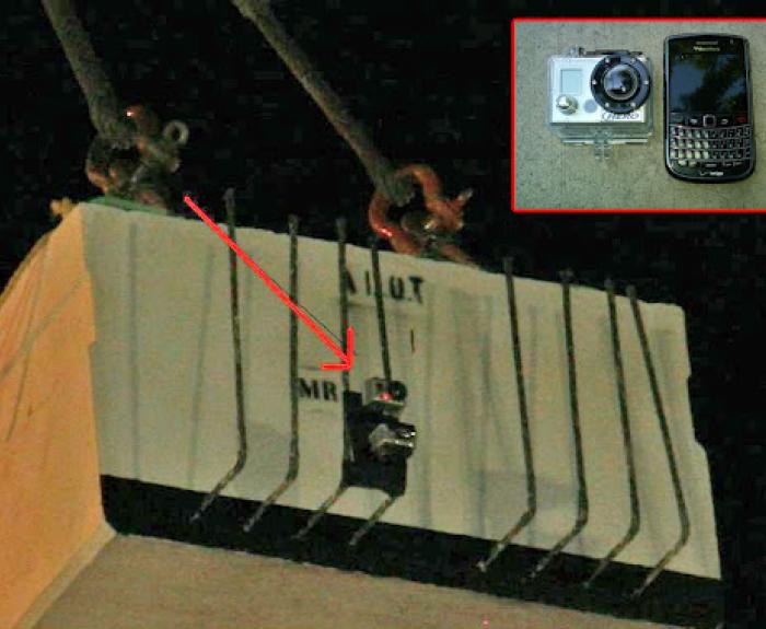 A small camera is attached to the side of a concrete block suspended by cables; an inset shows a camera and a mobile phone on a flat surface.
