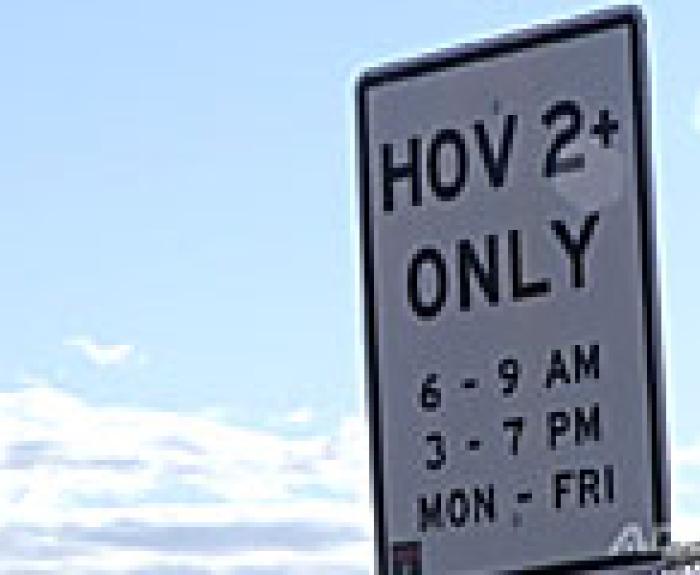 A road sign reads HOV 2+ ONLY, 6-9 AM, 3-7 PM, MON-FRI against a partly cloudy sky.