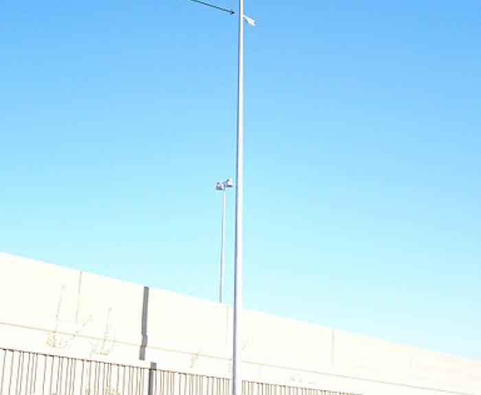 A tall, empty pole with an attached passive acoustic device stands next to a freeway.