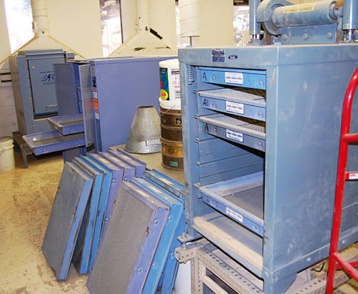 A materials testing lab for ADOT with blue drying racks and mesh screens stacked on the floor.