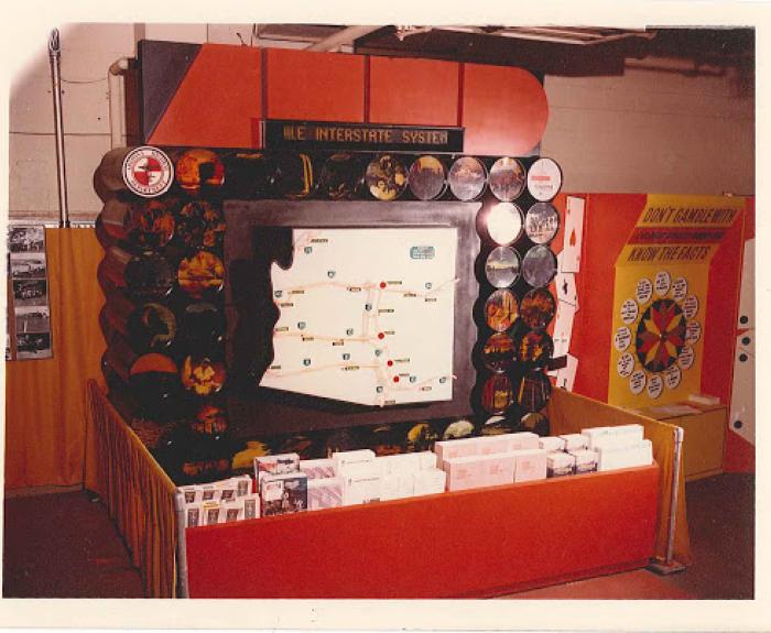 Exhibit display with a large map about the U.S. Interstate System, pamphlets, and a know the facts wheel.