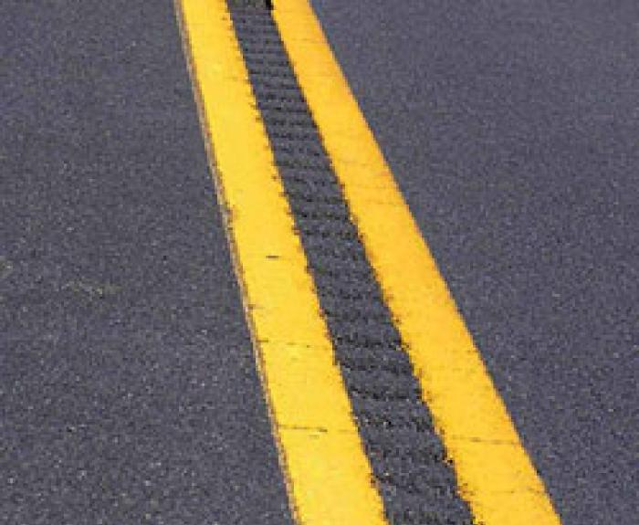 Close-up of a road with double yellow lines and recessed pavement markers