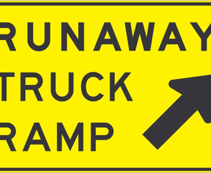 Yellow sign that reads "Runaway Truck Ramp" with an arrow pointing up
