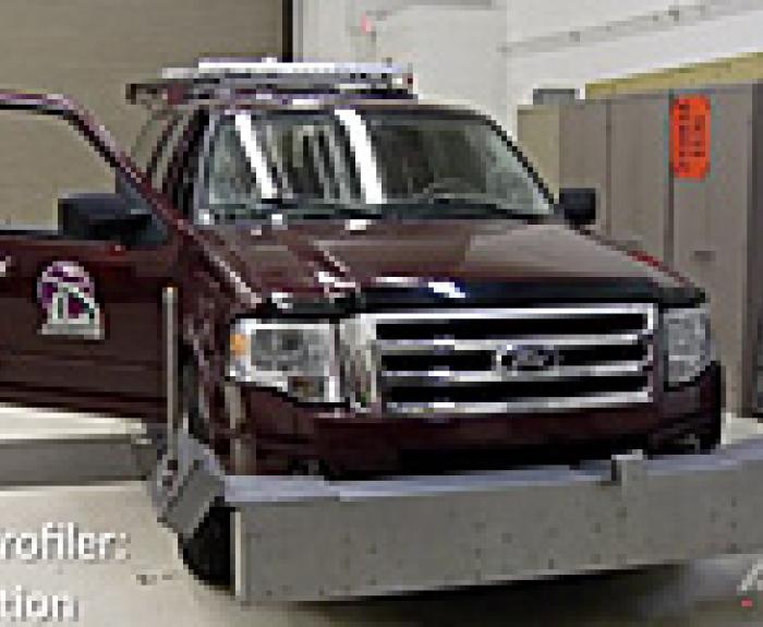 A maroon Ford SUV with equipment attached to the front is parked indoors with its driver door open. Text on the image reads Road Profiler: Calibration.