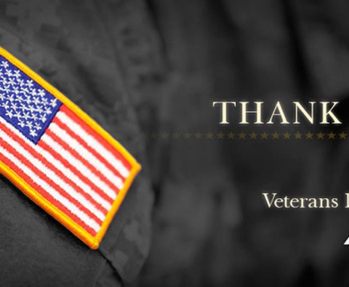 A U.S. flag patch on a uniform with the words Thank You and Veterans Day 2015 next to the ADOT logo on a dark background.