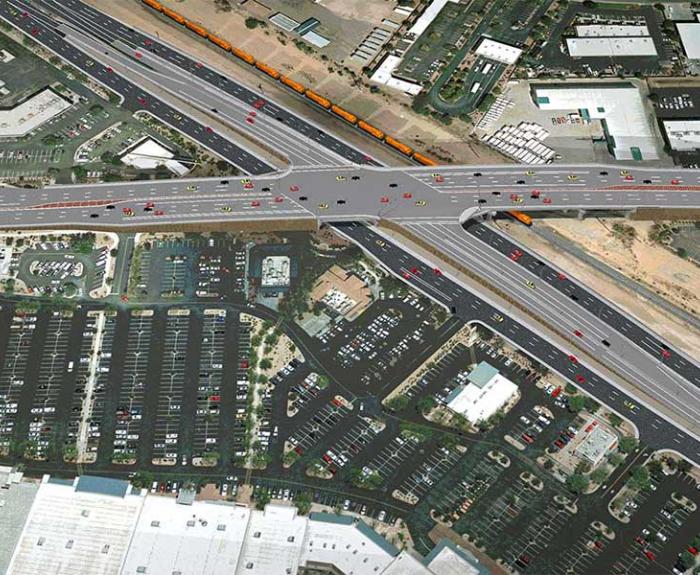 Aerial view of a busy highway interchange with many cars and nearby parking lots and buildings.