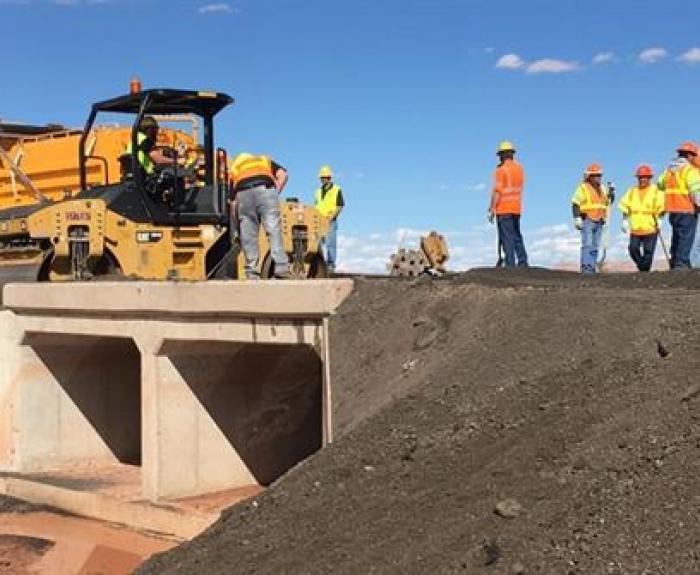 Workers and a roller complete repairs to a culvert on State Route 89.