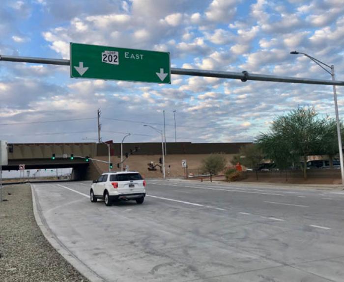 Vehicle passes under sign for new freeway interchange.