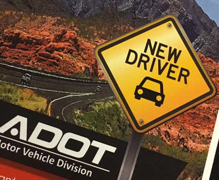 A graphic showing a road sign reading NEW DRIVER with a car icon is shown next to a winding road and mountains. The image includes the ADOT Motor Vehicle Division logo.