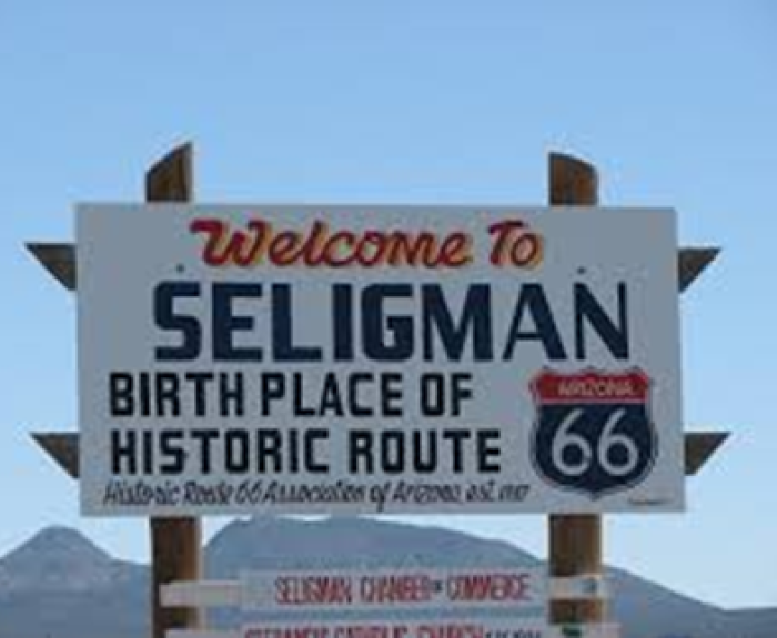 A large sign reads Welcome to Seligman, Birth Place of Historic Route 66 with mountains and blue sky in the background.