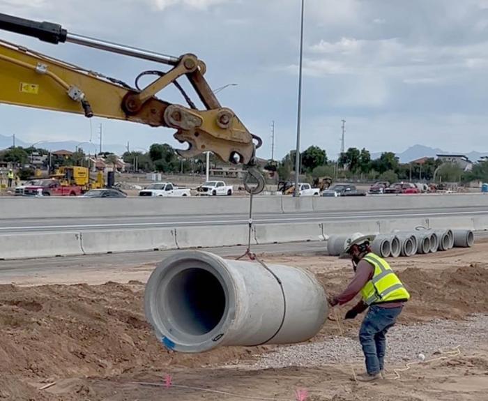 Crews lift a pipe used for drainage along Loop 202 in Chandler (ADOT file photo 2025)