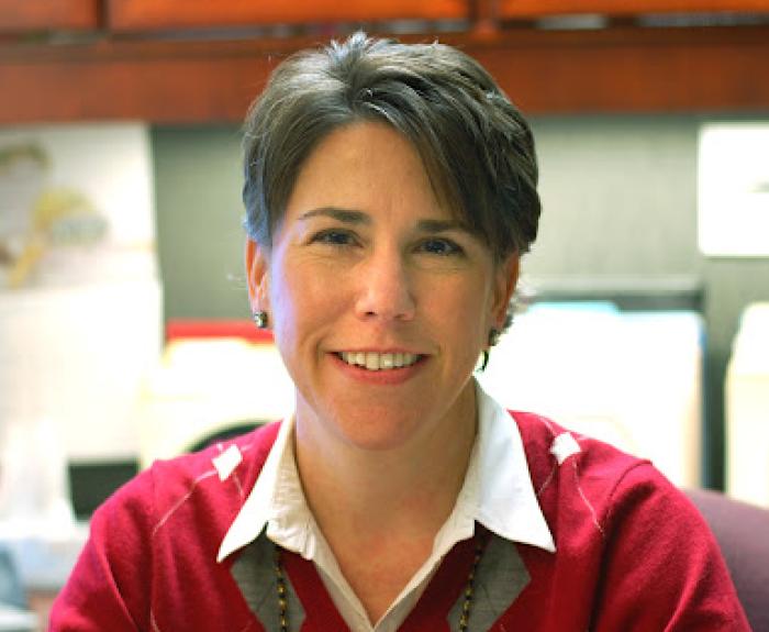 A woman at her desk poses for a photo.