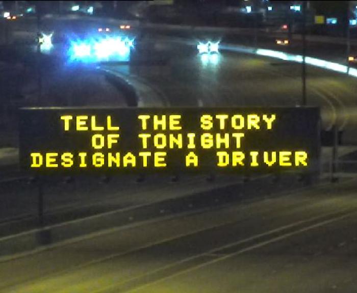 A digital message board over a highway encourages safe driving.