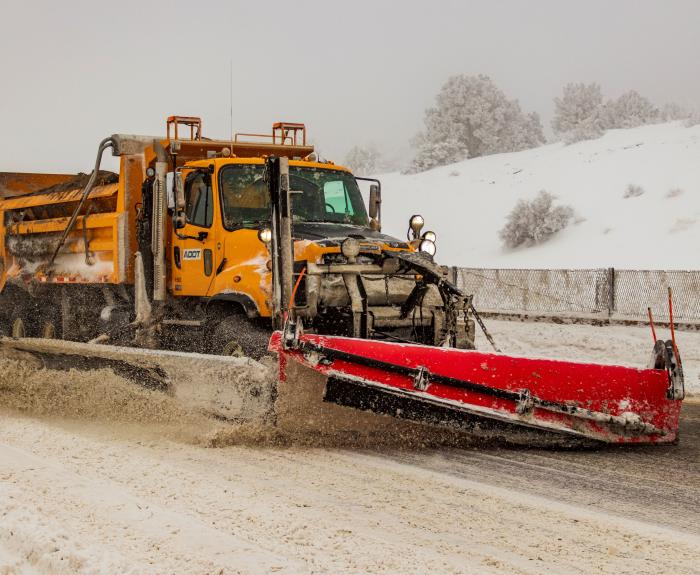 A snowplow on an icy highway plowing snow. 
