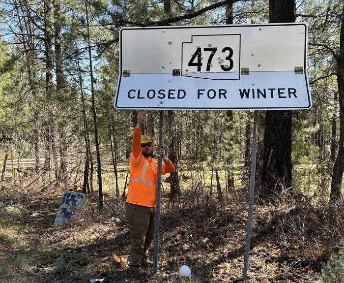 An ADOT worker reopens a rural highway after its seasonal closure for winter.