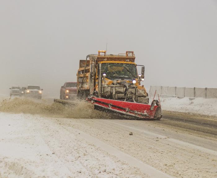 A snowplow on an icy highway plowing snow. 