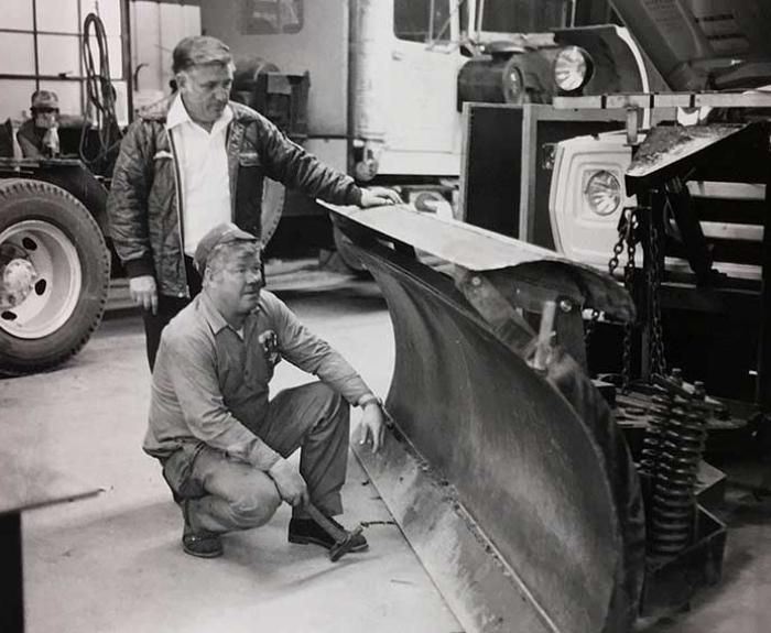 Crew members readying snow plow