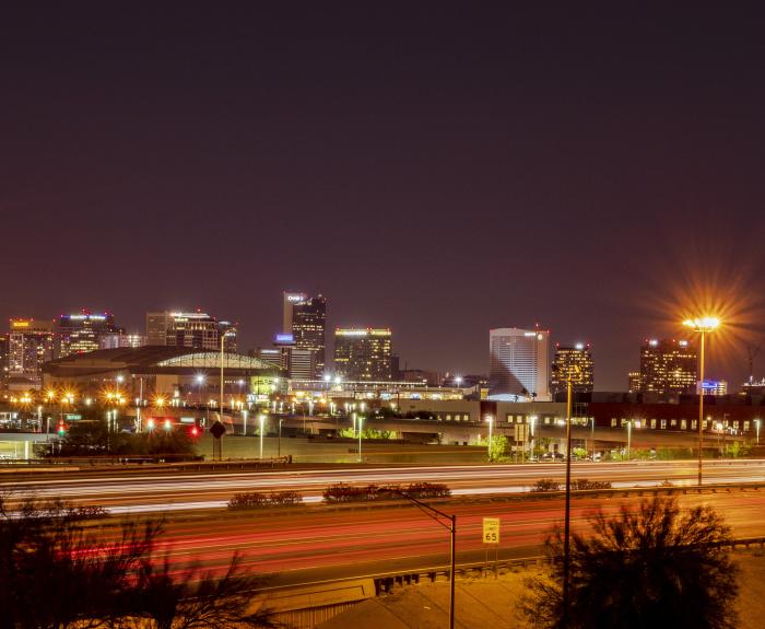 An urban freeway at night with a city skyline in the background.