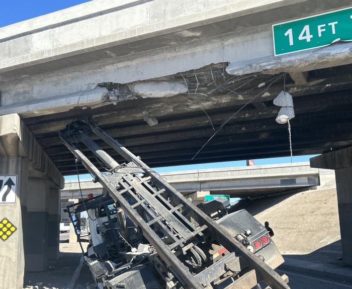 A crashed truck that struck the underside of a bridge. 