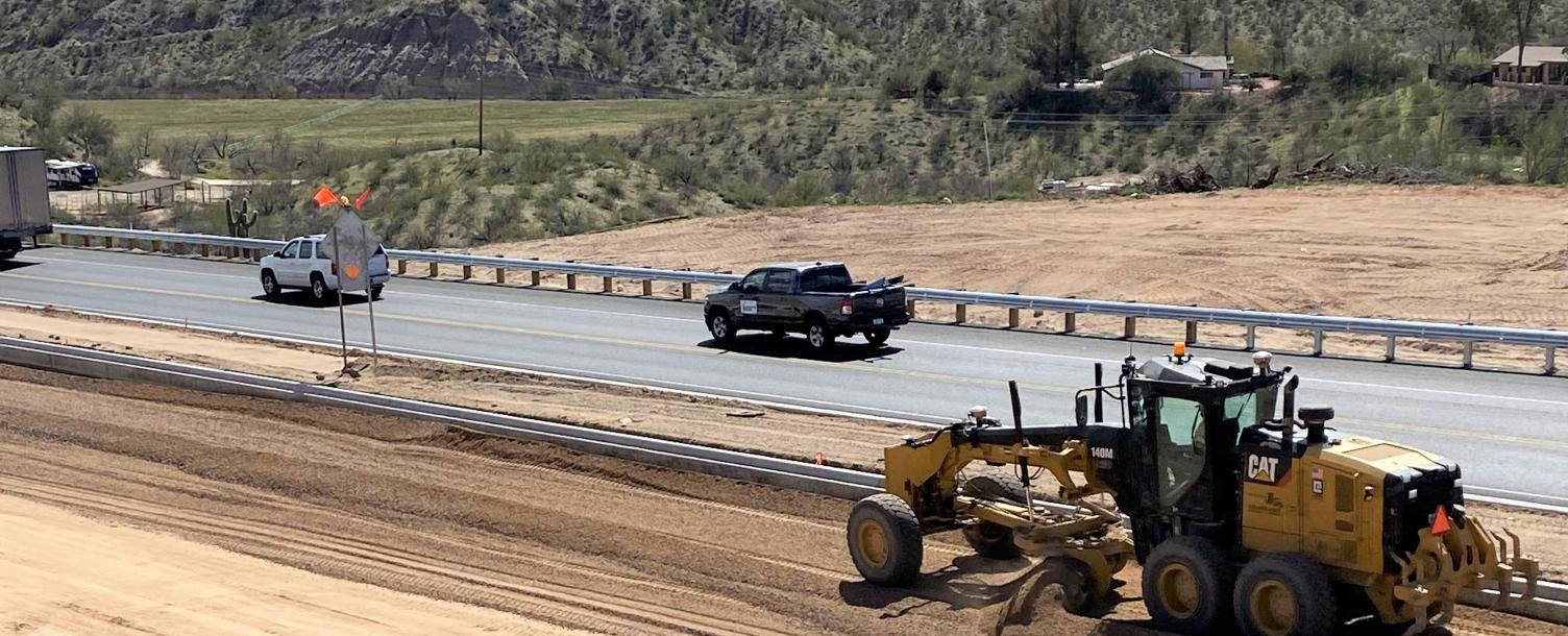 A grader spreads aggregate base course on the future northbound lanes as work progresses on the  US 93 widening project in Wickenburg. The base course, which serves as the sub-base layer of an asphalt roadway, is spread and compacted to provide a stable base for pavement. Paving of the new northbound lanes is scheduled to begin in March. (Photo courtesy of ADOT)